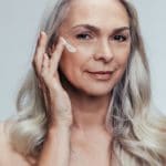 Mature woman putting on skin care cream