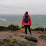 Woman standing on rocks looking at the ocean.